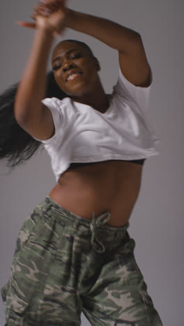 Vertical-Video-Studio-Portrait-Shot-Of-Young-Woman-Dancer-Dancing-In-Against-Grey-Background-In-Slow-Motion